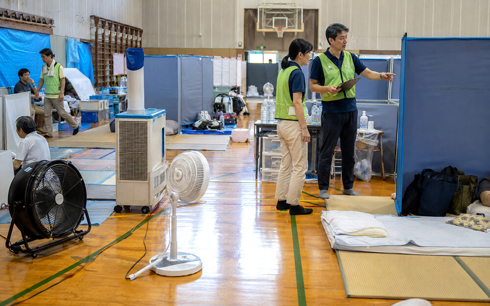 体育館避難所で工場扇とスポットクーラーを配置する様子