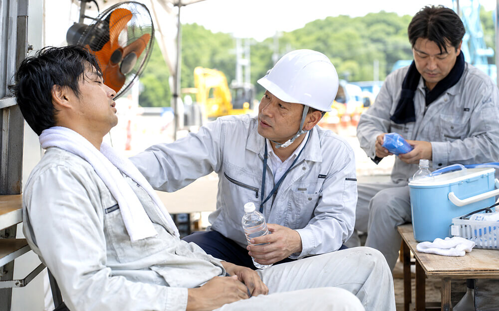 熱中症が疑われる作業者の意識や水分摂取可否を確認する様子