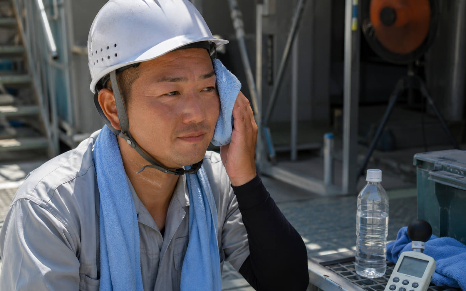 夏場のヘルメット内の蒸れと暑さを確認する作業員