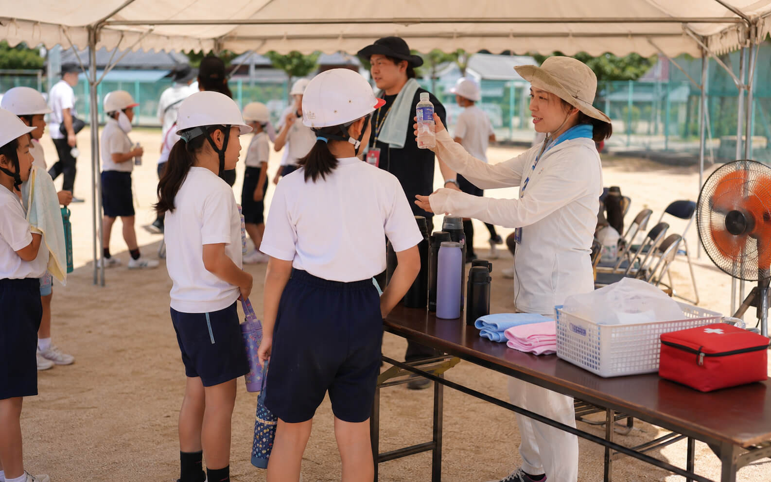 学校やイベントでヘルメット着用時の熱中症対策を行う様子