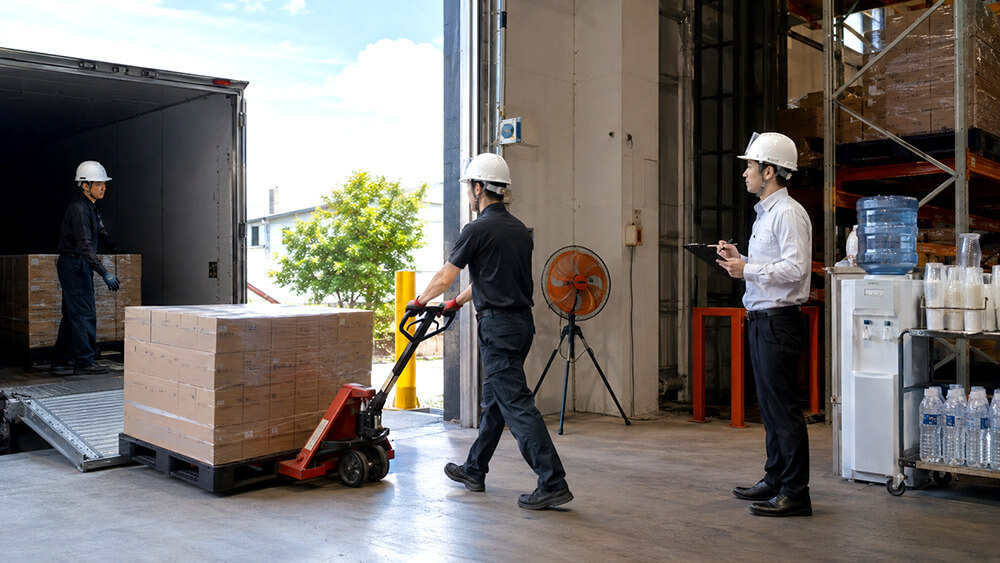 倉庫の荷下ろし作業でハンドパレットを使い身体負荷を減らす様子